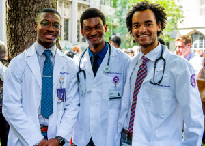 Three men in white coats smiling. Two of the men have stethoscopes draped over their shoulders.